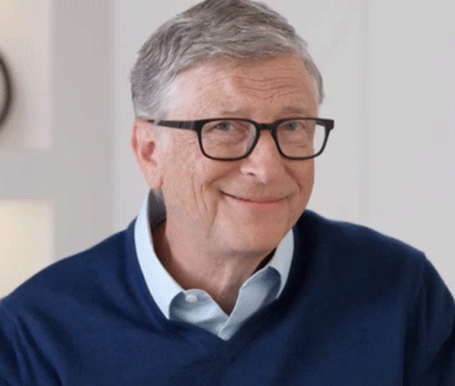 A man with glasses sitting in front of a clock.