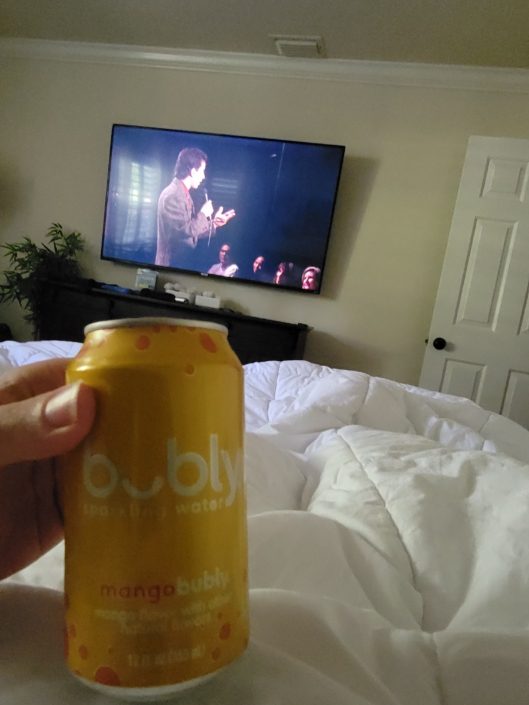 A person holding onto a can of soda in front of the television.