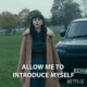 A woman standing in front of a car.