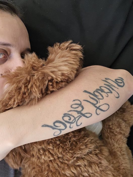 A woman with her arm around a teddy bear.