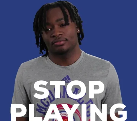 A man with dreadlocks is standing in front of the words stop playing.