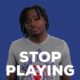 A man with dreadlocks is standing in front of the words stop playing.